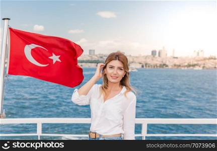 Beautiful woman travels with ferry between Asia and Europe with view of Turkish flag.Istanbul,Turkey. Beautiful woman travels with ferry between Asia and Europe