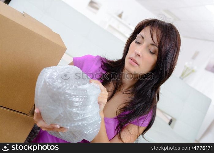 beautiful woman unpacking a carton box in her new home