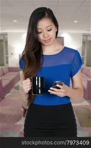 Beautiful woman using a cell phone will holding coffee
