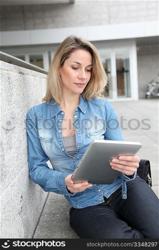 Beautiful woman using electronic tab in the street