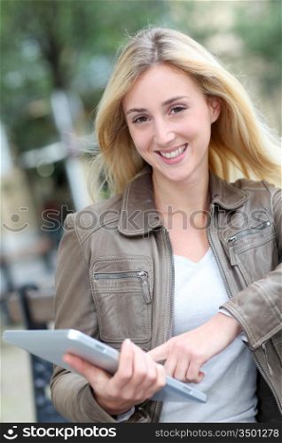 Beautiful woman using electronic tablet in public park