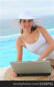 Beautiful woman using laptop computer by swimming-pool