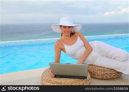 Beautiful woman using laptop computer by swimming-pool