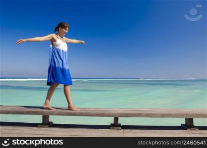 Beautiful woman walking with arms open on a beautiful tropical beach