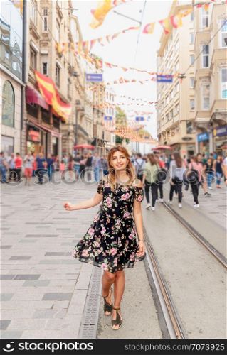 Beautiful woman walks at Istiklal street,a popular location in Beyoglu district,Istanbul,Turkey. Beautiful woman in red dress stands at Istiklal street