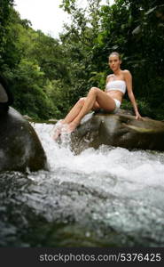 beautiful woman washing her feet in a spring stream