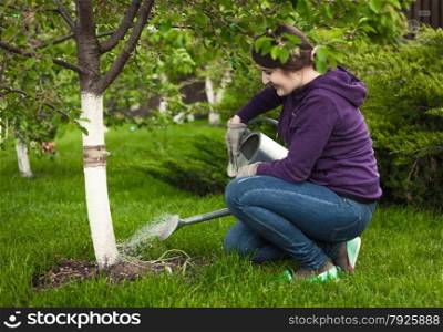Beautiful woman watering tree at garden with watering pot
