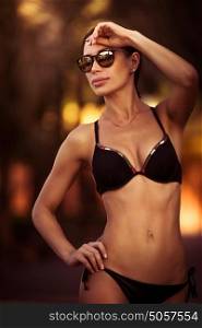Beautiful woman wearing bikini, gorgeous fashion model posing in stylish swimsuit and sunglasses, attractive female with perfect body