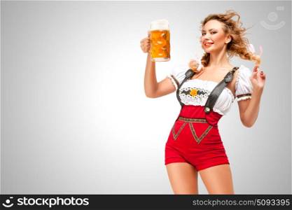 Beautiful woman wearing red jumper shorts with suspenders as traditional dirndl, serving two beer mugs on grey background.