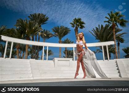 Beautiful woman wearing swimsuit and pareo standing against the background of the amphitheater.. Beautiful woman wearing swimsuit and pareo standing against the background of the amphitheater