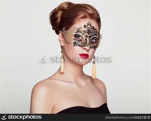 Beautiful Woman Wearing Venetian Masquerade Carnival Mask at Party, over White Background. Christmas and New Year Celebration. Sexy Girl with Holiday Makeup and Red lips. Golden Mask