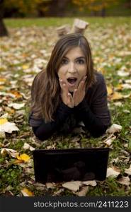 Beautiful woman with a astonish expression working with a laptop in outdoor