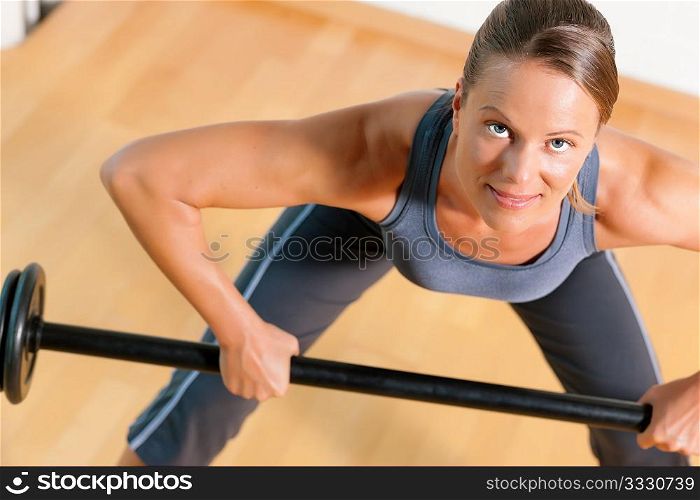 Beautiful woman with a barbell exercising in gym
