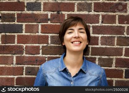 Beautiful woman with a happy expression in front of a brick wall