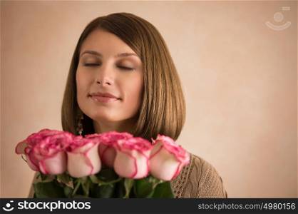 Beautiful woman with a large bouquet of flowers in her arms smelling a fragrant pink rose