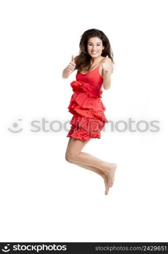 Beautiful woman with a red dress jumping and with thumbs up, isolated on white
