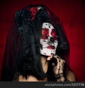 beautiful woman with a sugar skull makeup with a wreath of flowers on her head, red background