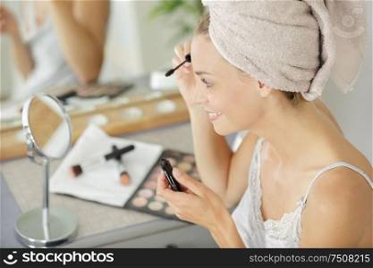 beautiful woman with a towel on her head doing make-up