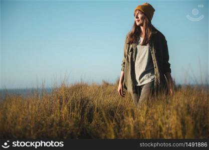 Beautiful woman with a yellow cap and walking over high grass
