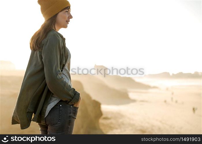 Beautiful woman with a yellow cap looking to the beach enjoying the view