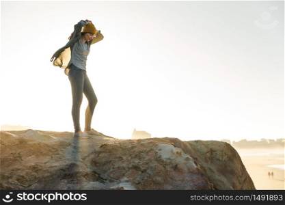 Beautiful woman with a yellow cap on a cliff over the beach