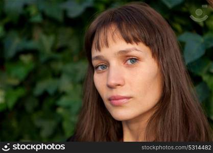 Beautiful woman with blue eyes and brown hair in the park