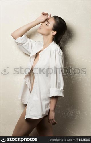 beautiful woman with brown hair and perfect skin in fashion pose with unbuttoned white shirt and nude legs
