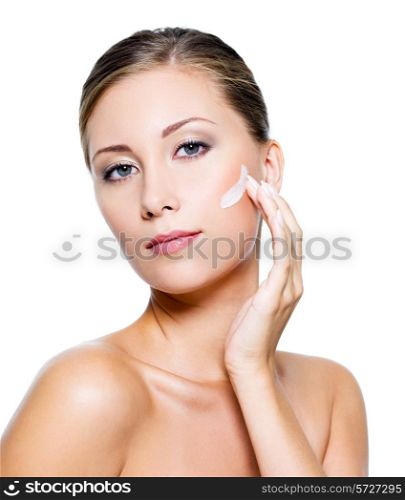 Beautiful woman with clean skin applying cosmetic cream on face