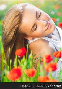 Beautiful woman with closed eyes lying down on poppy flower field, relaxation outdoors on fresh gentle floral meadow, enjoying spring nature&#xA;