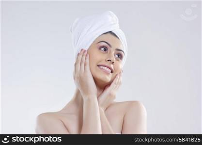 Beautiful woman with hair wrapped in towel looking away against white background