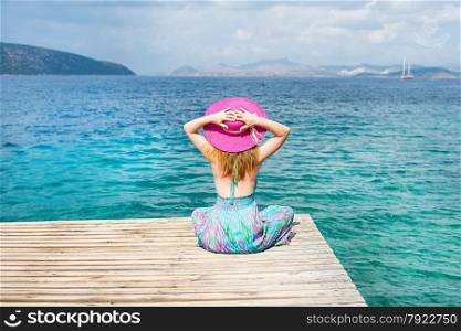Beautiful woman with hat sitting at the beach