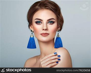 Beautiful Woman with Large Earrings Tassels jewelry Blue color. Perfect Makeup and Elegant Hairstyle. Blue Make-up Arrows
