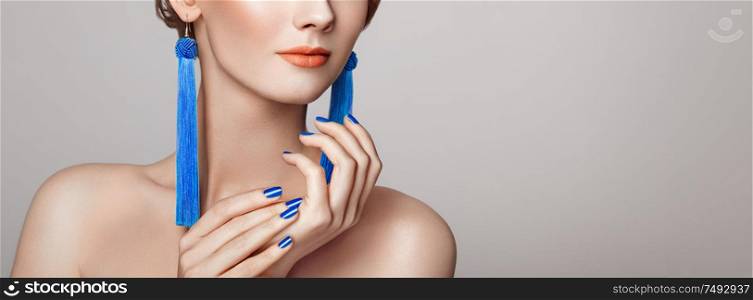 Beautiful woman with large earrings tassels jewelry blue color. Perfect makeup and nails manicure