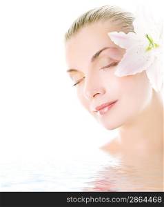 Beautiful woman with lily flower in her hair reflected in water