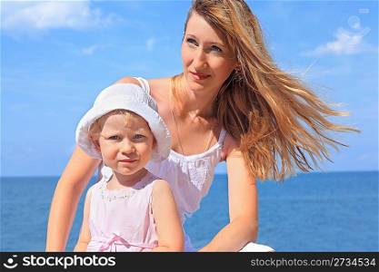 beautiful woman with little girl in white hat near sea