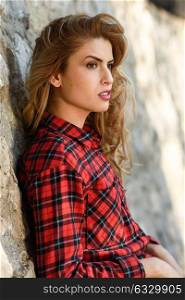 Beautiful woman with long blond curly hair. Girl in checkered shirt.