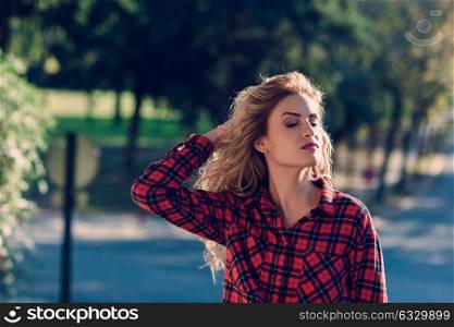 Beautiful woman with long blond curly hair. Woman in checkered shirt and blue jeans