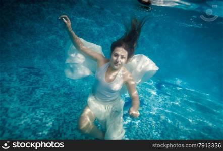 Beautiful woman with long hair swimming underwater at pool