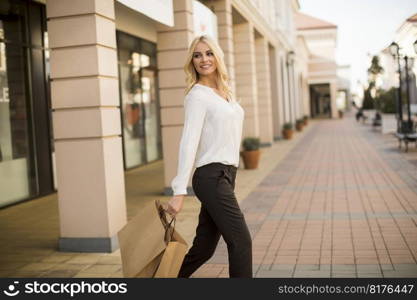 Beautiful woman with paper shopping bag walking by the stores