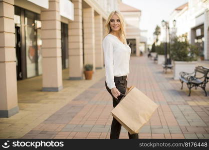 Beautiful woman with paper shopping bag walking by the stores