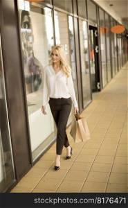 Beautiful woman with paper shopping bag walking by the stores