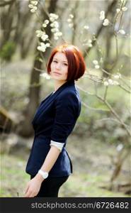 Beautiful woman with red hair in business suit posing outdoors