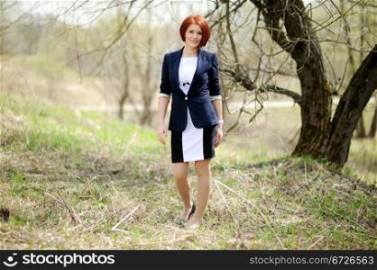 Beautiful woman with red hair in business suit posing outdoors