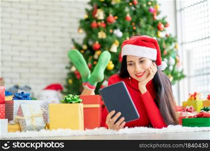 Beautiful woman with rest one or s hands hold tablet and stay in room with Christmas tree look like she happy with online shopping at home during Christmas festival.