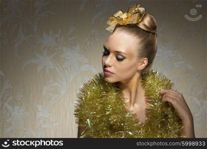 beautiful woman with shiny artistic christmas make-up, sparkle tinsel around neck and golden ribbon on hair-style