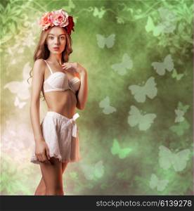 beautiful woman with spring flowers on the head and vintage lingerie posing with romantic expression and natural make-up