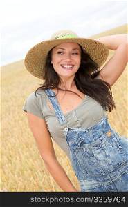 Beautiful woman with straw hat standing in wheat field
