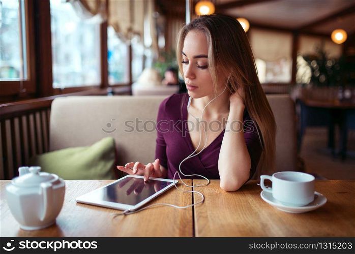 Beautiful woman with tablet pc using internet in restaurant. Girl with modern gadget using 4g in restaurant.. Woman with tablet pc using internet in restaurant.