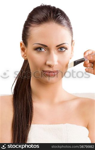 beautiful woman with white towel getting a beauty treatment with brush on face