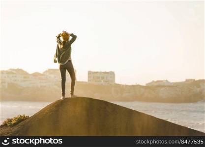 Beautiful woman with yellow cap over the cliff seeing the beach